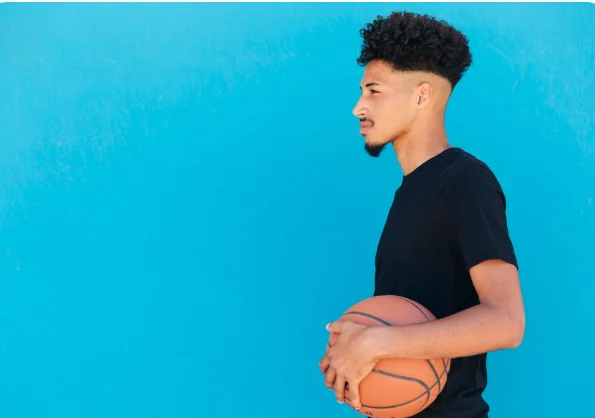 Man sporting natural curly hair on top with tapered fade on the sides.