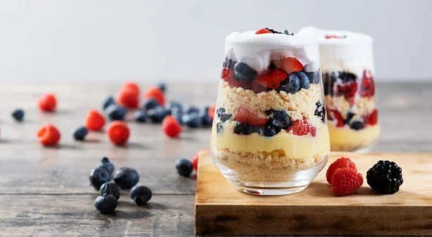 Trifle dessert with berries and cream on wooden table