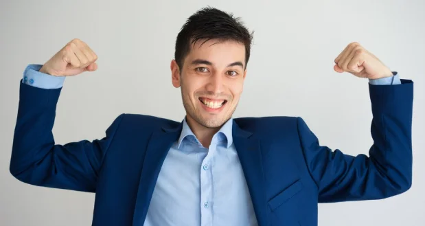 Portrait of cheerful young caucasian businessman showing muscles-personal growth counseling