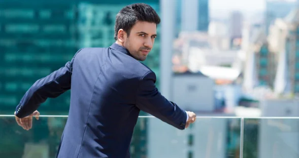 Elegant man leaning on a railing looking back-personal growth coach