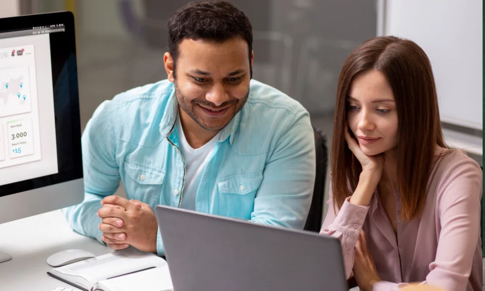 Business professional showing B2B SEO tool dashboard on laptop to coworker