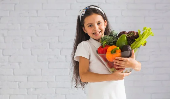 Smiling girl holding fresh organic vegetables in glass bowl-cheap veggie dishes