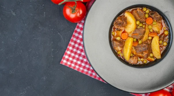 meat soup with garniture on round plate fresh tomatoes on black-8 hour crock pot recipes