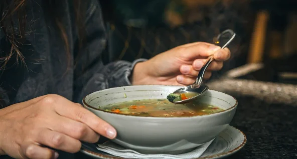 A woman in a cafe eats a lowcalorie vegetable soup-crockpot potluck ideas