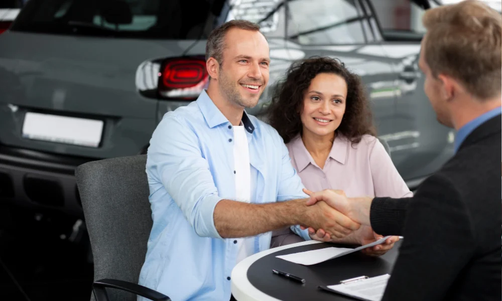 Customer shaking hands with a car salesman after purchase.