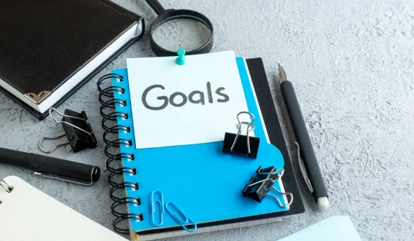 goals written note with notepad and pen