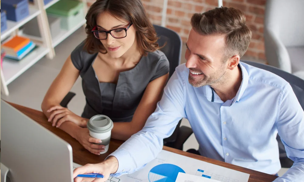 Happy business owner looking at increased sales reports with SEO consultant