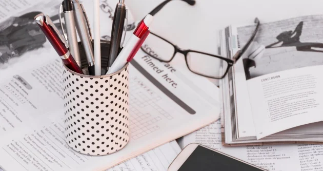 Pens and smartphone on copybooks near glasses
