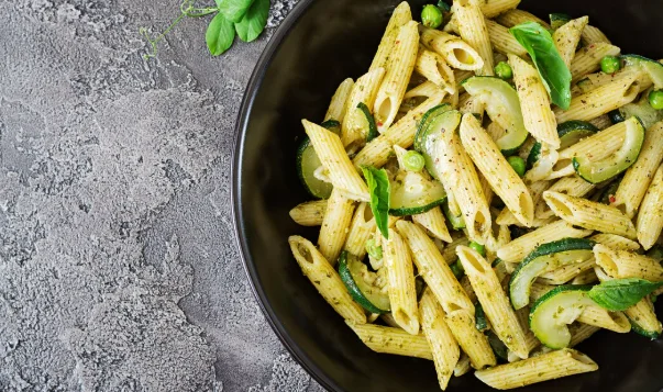 Penne pasta with pesto sauce, zucchini, green peas and basil