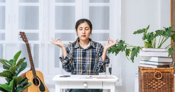 A woman sitting at the table working at the table and making a sign with a hand ok