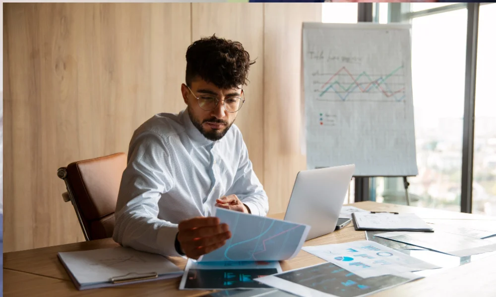 Professional working with financial charts and salary data sheets spread on a desk