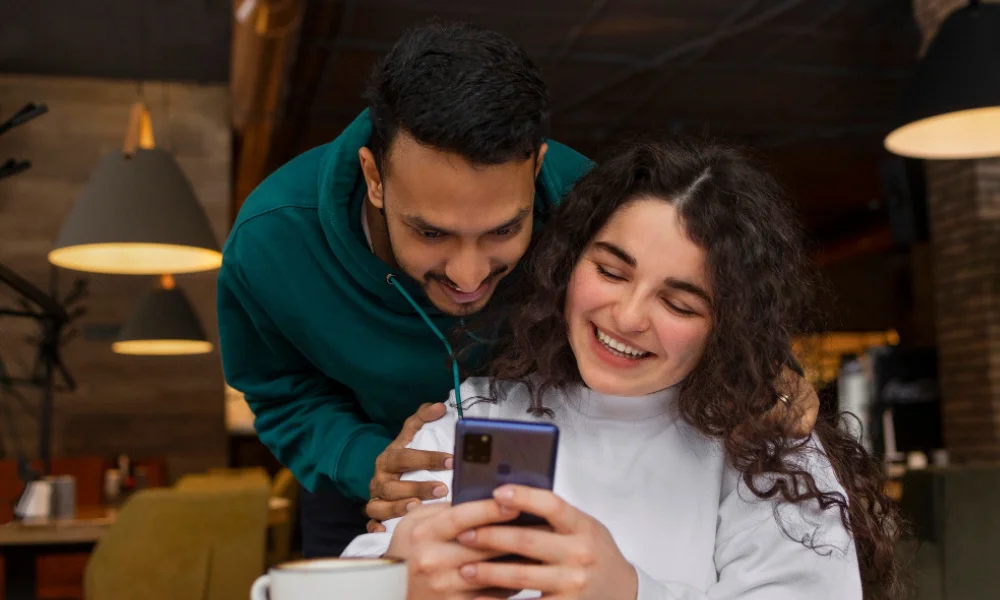 Smiling couple leaving a 5-star review on smartphone