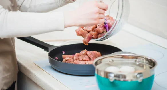 Person putting raw meat on pan-crock pot pressure cooker