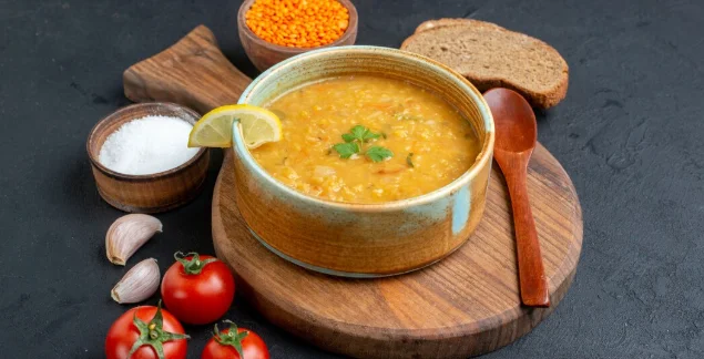 lentil soup with salt tomatoes and dark bread loafs on dark surface-cheap family dinner recipes