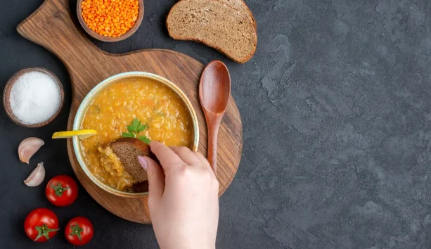 lentil soup with salt tomatoes and dark bread loaves on dark surface-cheap easy crock pot meals