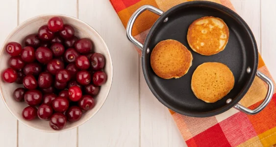 pancakes in pan and cherries on plaid cloth and in bowl-crockpot recipes for two