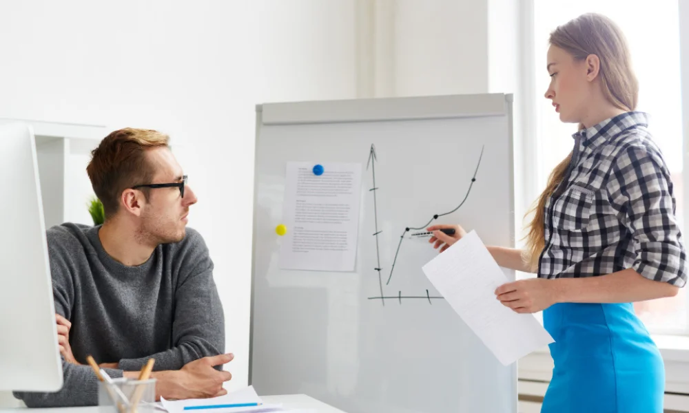 A marketing team in a meeting reviewing website content strategy on a whiteboard.
