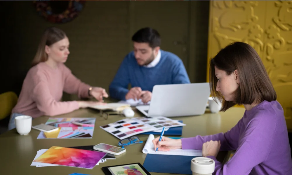 Close-up of creative team working with branding sketches and laptop on table