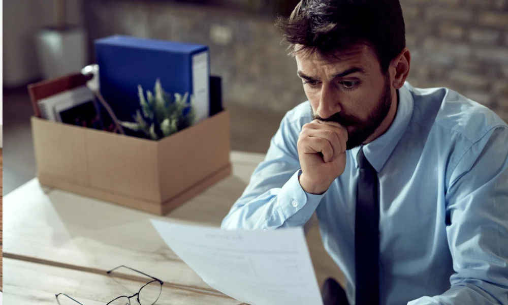 Concerned freelancer looking at contract papers at desk.