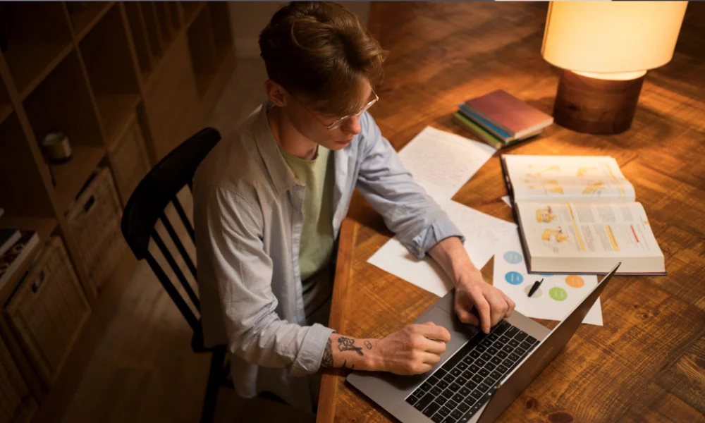 Entrepreneur writing notes on branding strategy while working on laptop.