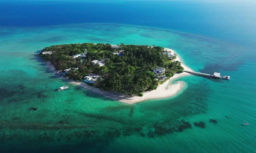 An aerial view of Banwa Private Island in the Philippines, featuring lush greenery, white sand beaches, and luxury beach villas surrounded by turquoise waters, showcasing one of the best private island resorts.