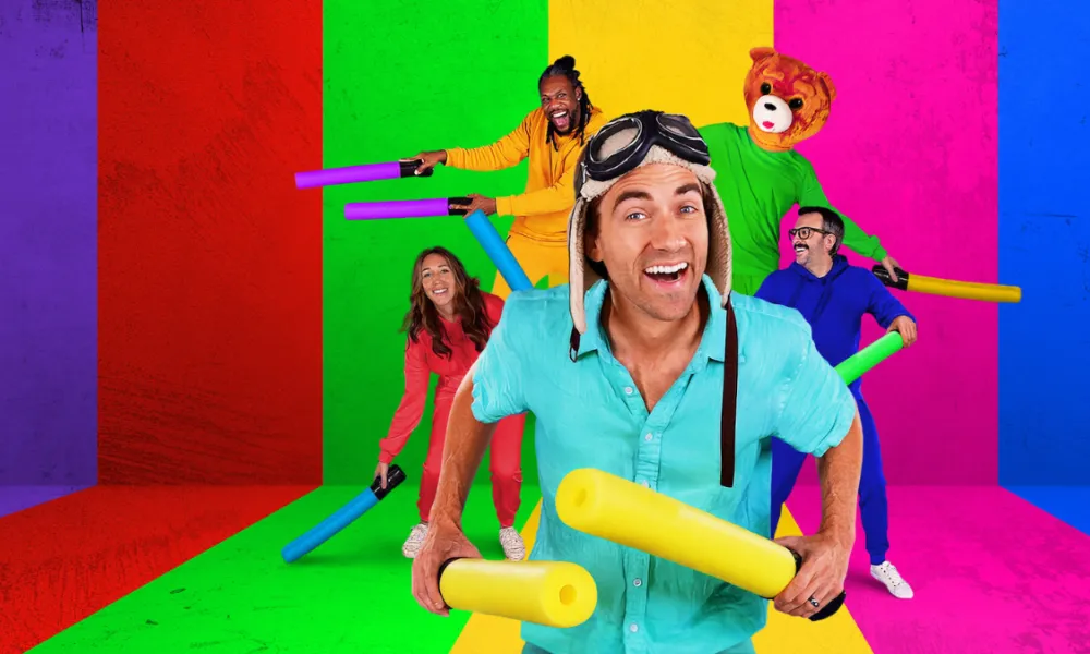 Danny Go Net Worth featured in a colorful promotional image of children's entertainer Danny Go wearing an aviator cap surrounded by his energetic cast holding foam props.