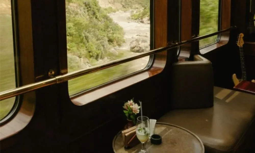 Panoramic view of a mountain river valley from the observation car of the Hiram Bingham train with leather seating and cocktails, ideal for luxury train journeys.