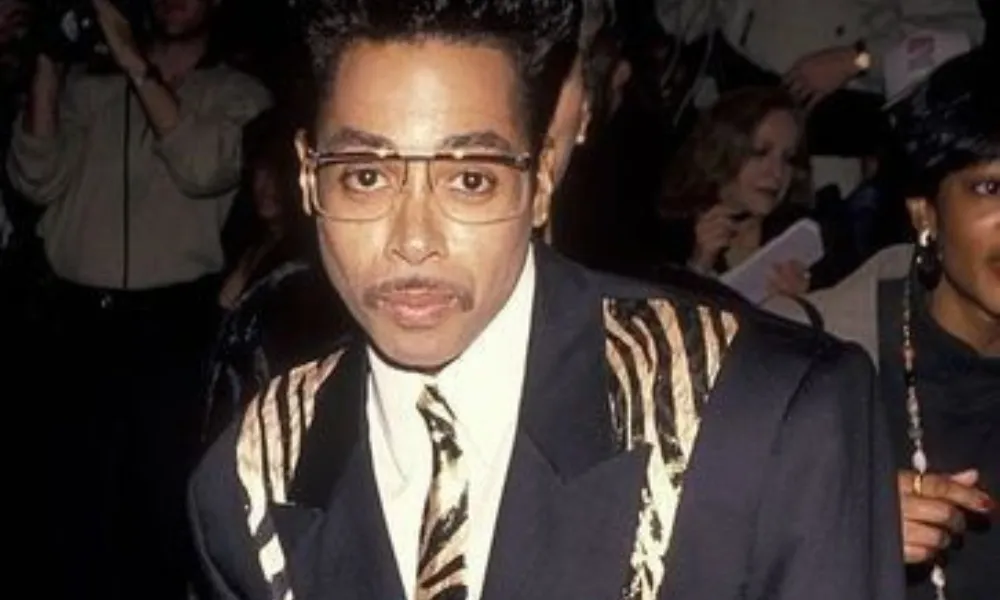 Morris Day Net Worth featured in a photo of the funk musician wearing a zebra-patterned suit jacket and matching tie.