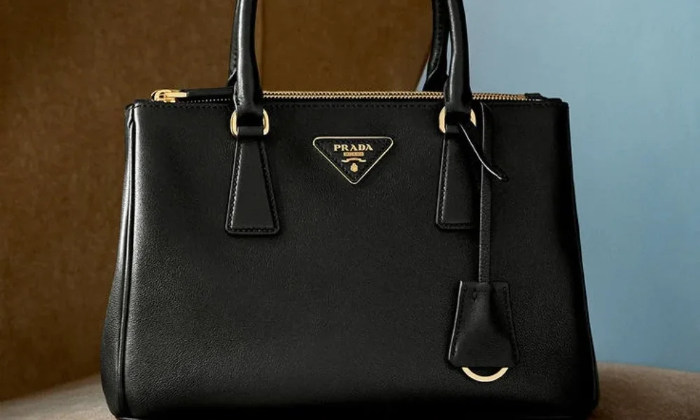 A black leather Prada Galleria handbag featuring gold hardware and the signature inverted triangle logo, demonstrating timeless handbag design when considering if luxury brands worth investing