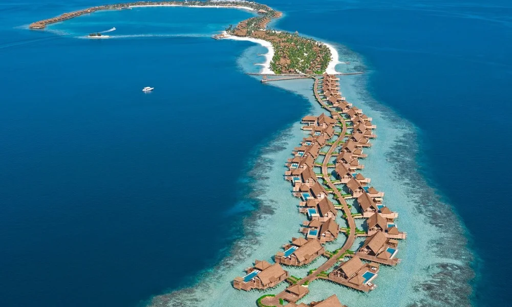 An aerial view of the Waldorf Astoria Maldives Ithaafushi showing a long boardwalk with luxury overwater villas extending into clear ocean waters, representing one of the best private island resorts.