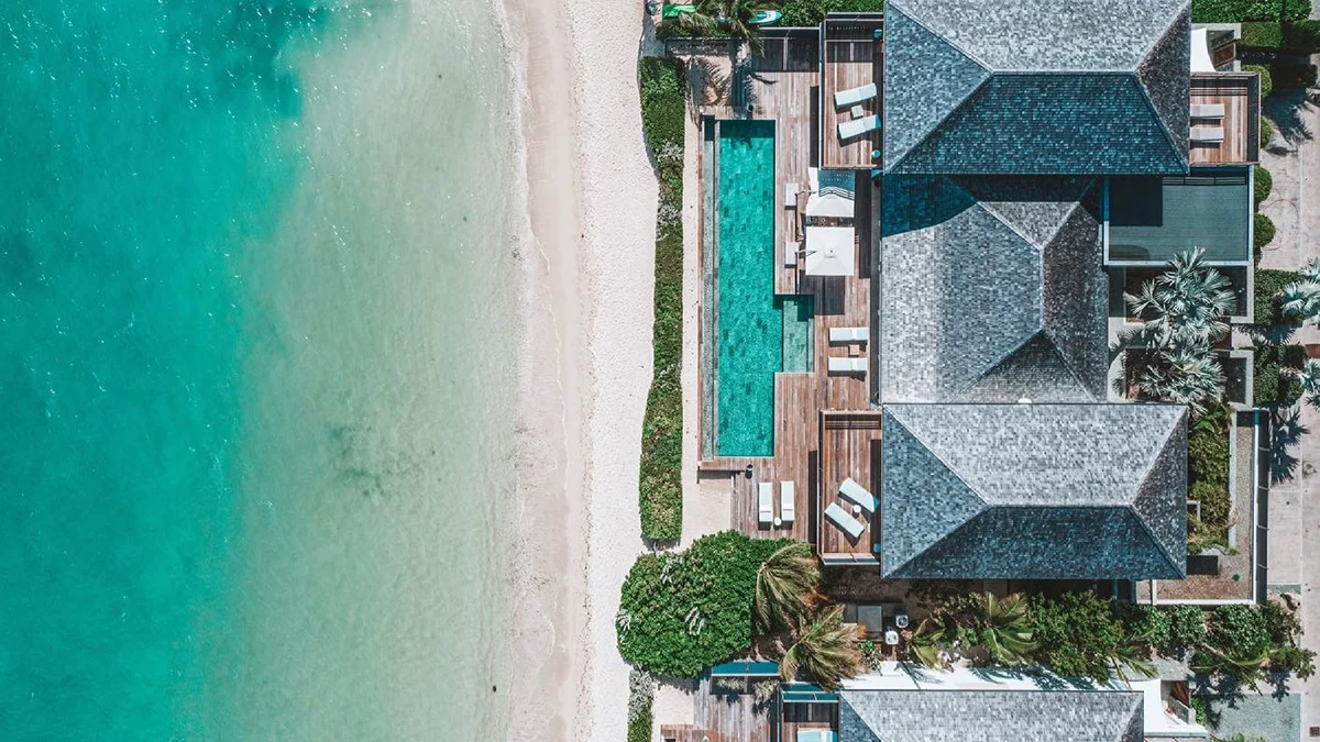 Aerial top-down view of a luxury beachfront villa in St. Barts featuring a private lap pool along a sandy white beach and clear turquoise water.