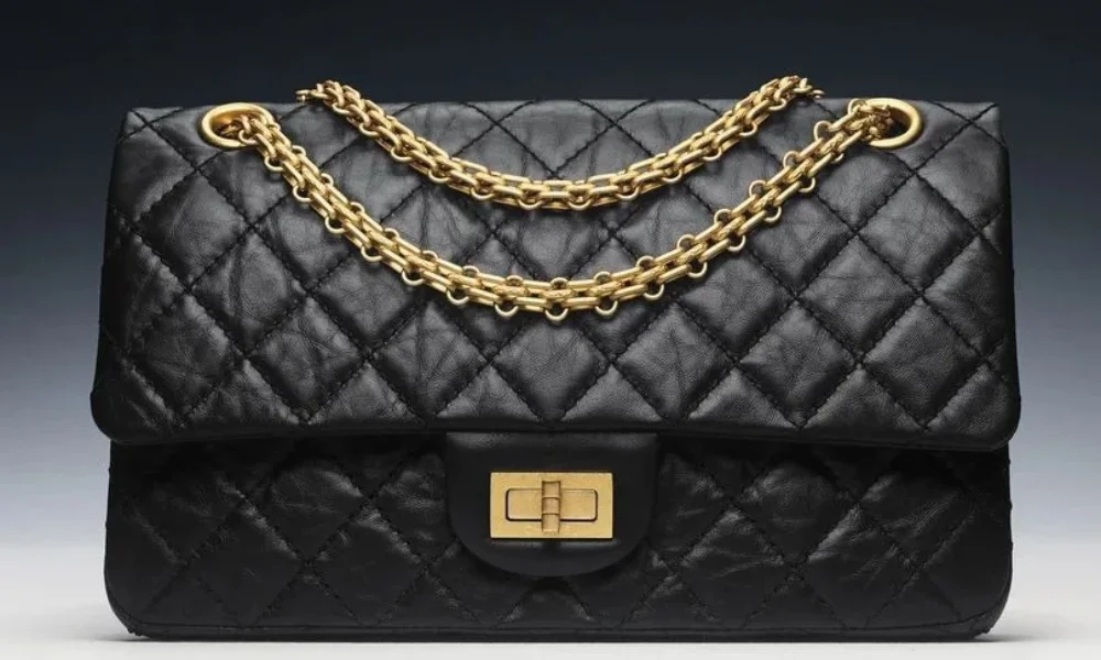 A classic black quilted leather Chanel 2.55 handbag featuring a gold chain strap and turn-lock closure, perfect for luxury fashion posts