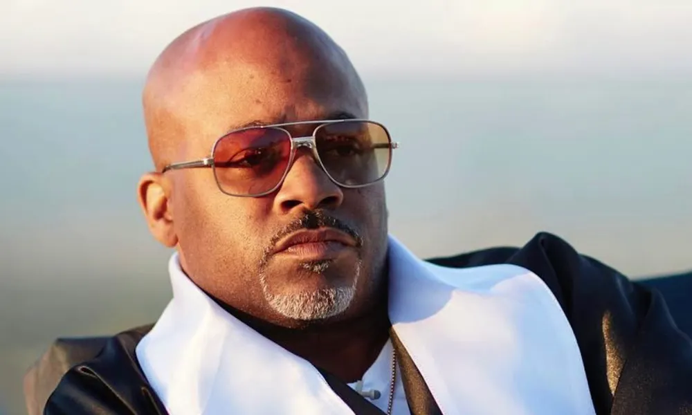 dame dash net worth highlighted in a close-up photo of Damon Dash wearing aviator sunglasses and a black-and-white suit jacket.