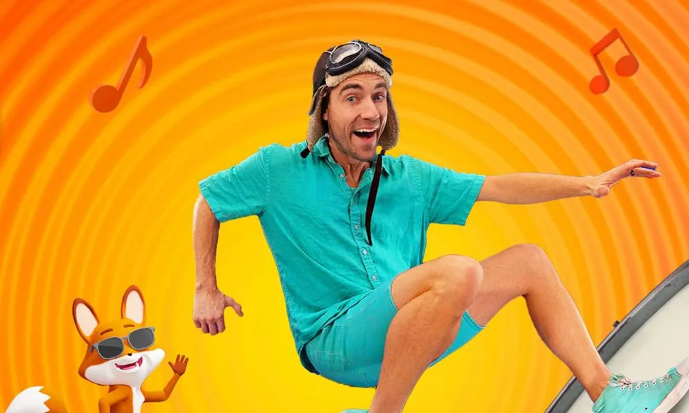 Danny Go Net Worth featured in a colorful graphic of children's host Danny Go leaping over drums alongside an animated fox character.