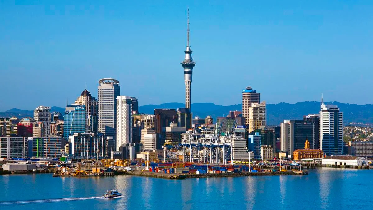 Auckland city skyline anchored by the iconic Sky Tower rising above Waitematā Harbour in New Zealand.