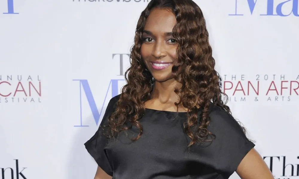 Rozonda "Chilli" Thomas poses on the red carpet in a black dress, highlighting her multi-decade career in entertainment and interest in the Rozonda Thomas net worth.