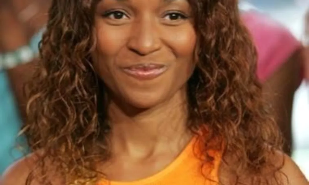 A close-up shot of Rozonda Thomas wearing an orange top, providing visual context for articles detailing the Rozonda Thomas net worth and career milestones.