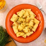 italian pasta cooked tasty salted inside round orange plate with greens and raw pasta