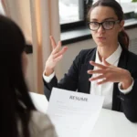 Confident millennial female applicant in glasses talking at job interview