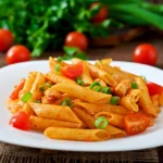 Penne pasta in tomato sauce with chicken and tomatoes on a wooden table
