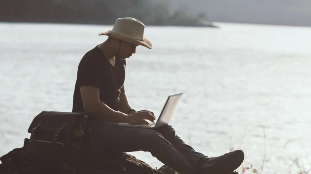 Traveler working on laptop outdoors learning how to start a travel blog.