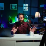 YouTuber recording video with camera, lights, and laptop open