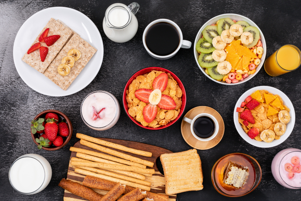 breakfast with fruits, toasts, cornflakes, yogurt on black surface