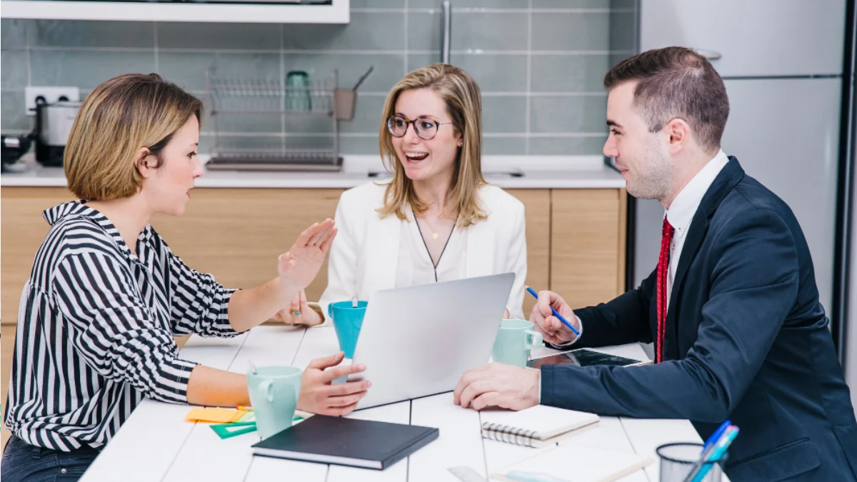 Team of SEO specialists discussing audit checklist with papers and laptops around table.