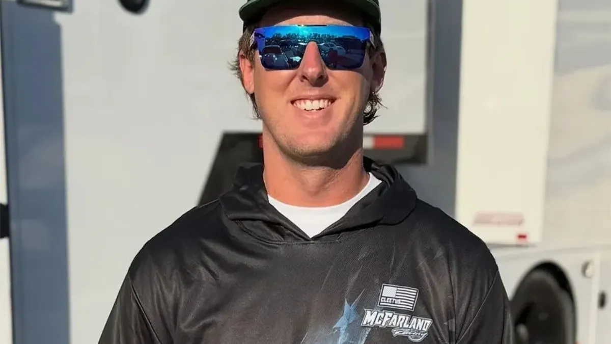 Cleetus McFarland Net Worth featured in a photo of a smiling Garrett Mitchell wearing blue sunglasses and a Cleetus McFarland hoodie outdoors.