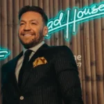 Conor McGregor posing in front of a Road House neon sign featuring Conor McGregor Net Worth