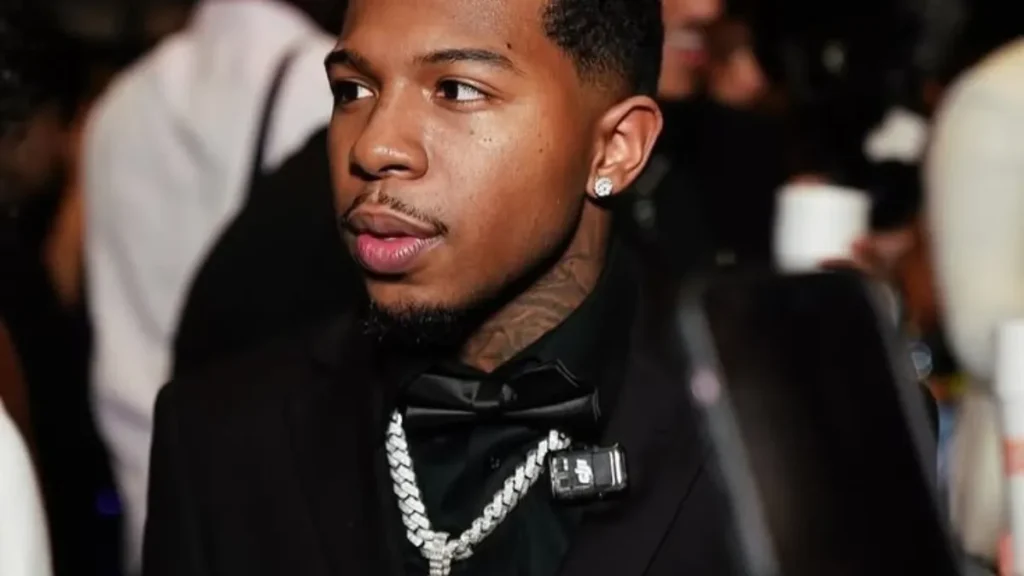 Deshae frost net worth 2026 reflects his successful career, pictured here wearing a black suit with a diamond chain at a formal event.