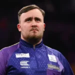 Luke Littler maintains a serious expression during a tournament appearance, illustrating the prominence of the young player and discussions around Luke Littler net worth.